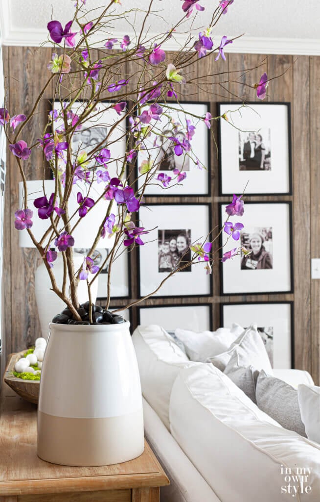 Faux blooming branches in large planter behind a sofa