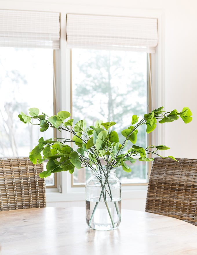 Faux gingko stems in vase on water on kitchen table