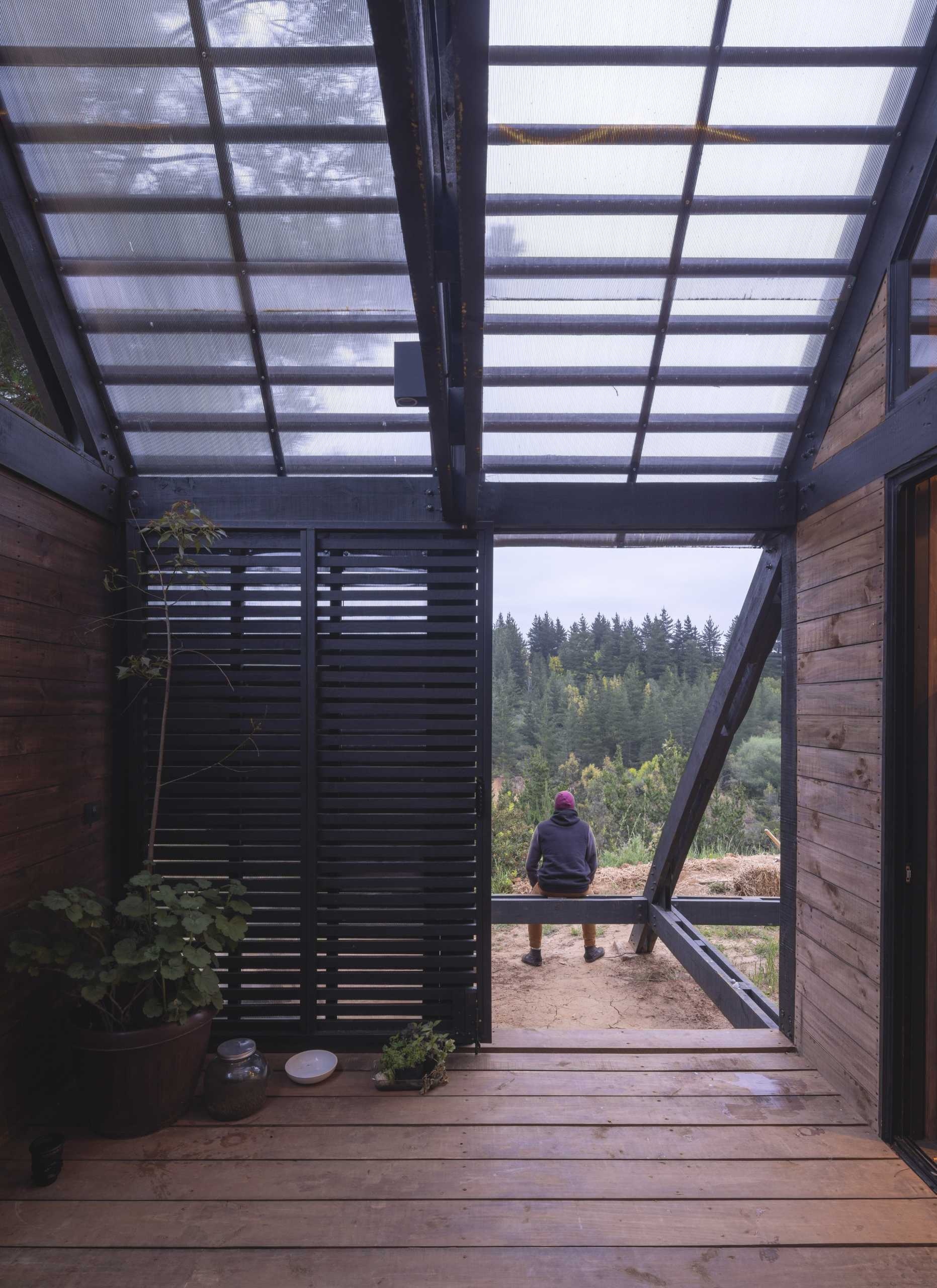 A small home in the forest with a sliding slat door.