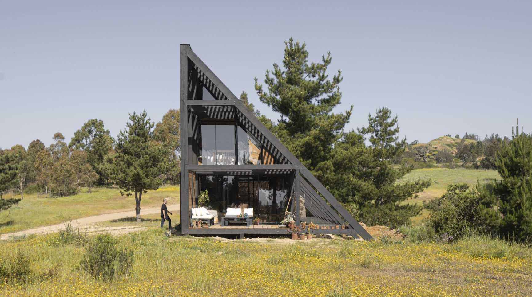 A small wedge-shaped home with a black exterior that's located on the windy beach of Matanzas, Chile.