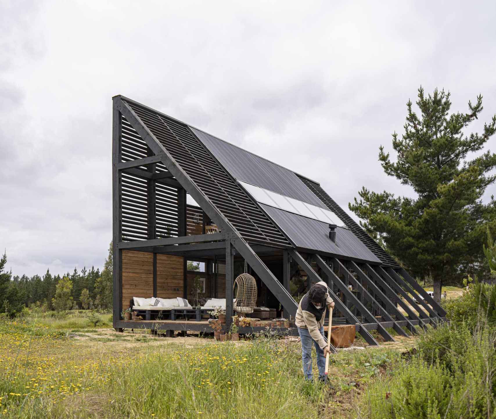 A small wedge-shaped home with a black exterior that's located on the windy beach of Matanzas, Chile.