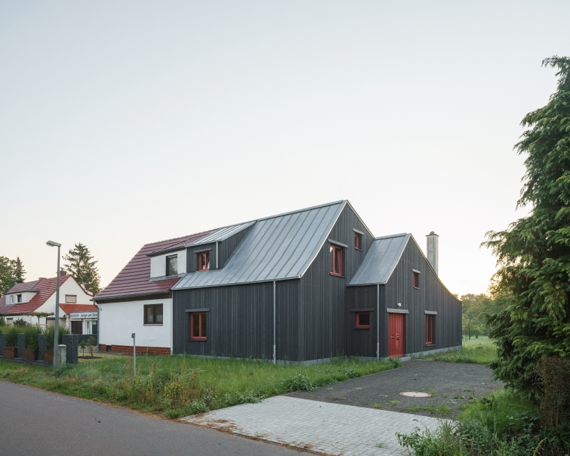 dark wooden facade by ko/ok architektur contrasts semi-detached gabled house in germany