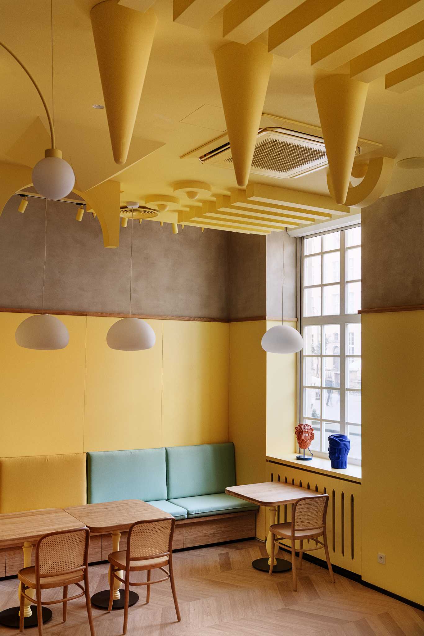 A modern dessert cafe with a bright yellow interior and sculptural ceiling.