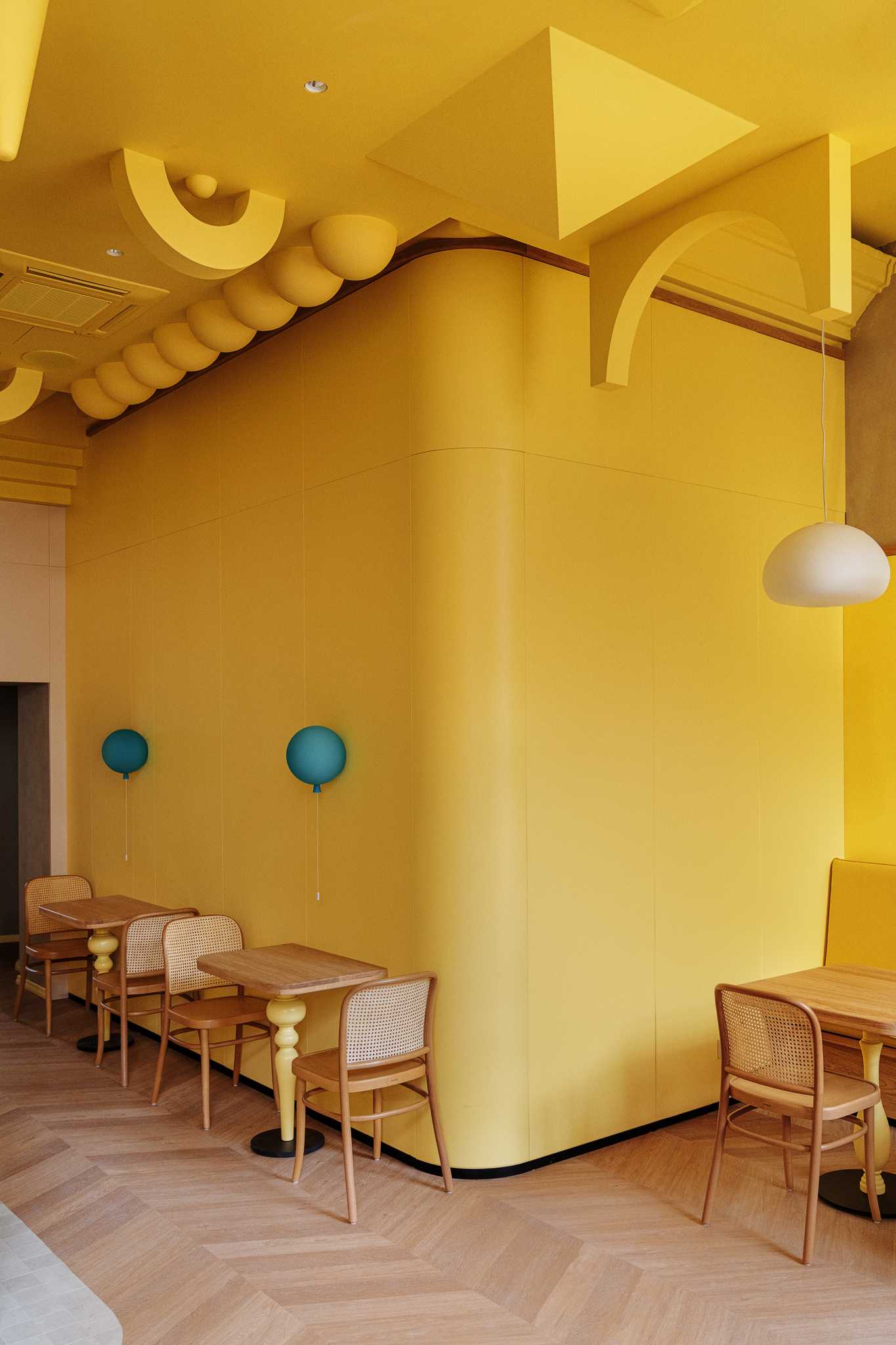 A modern dessert cafe with a bright yellow interior and sculptural ceiling.