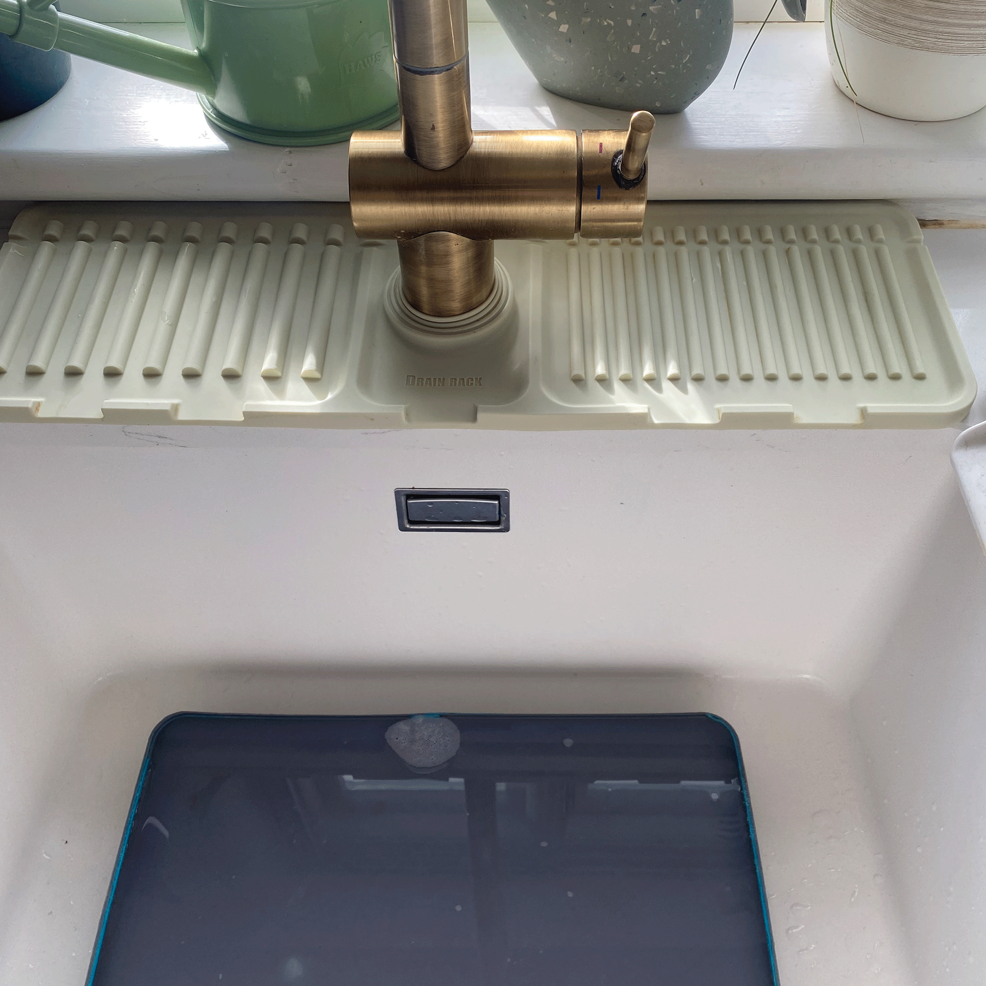 White kitchen sink with gold tap and sink guard