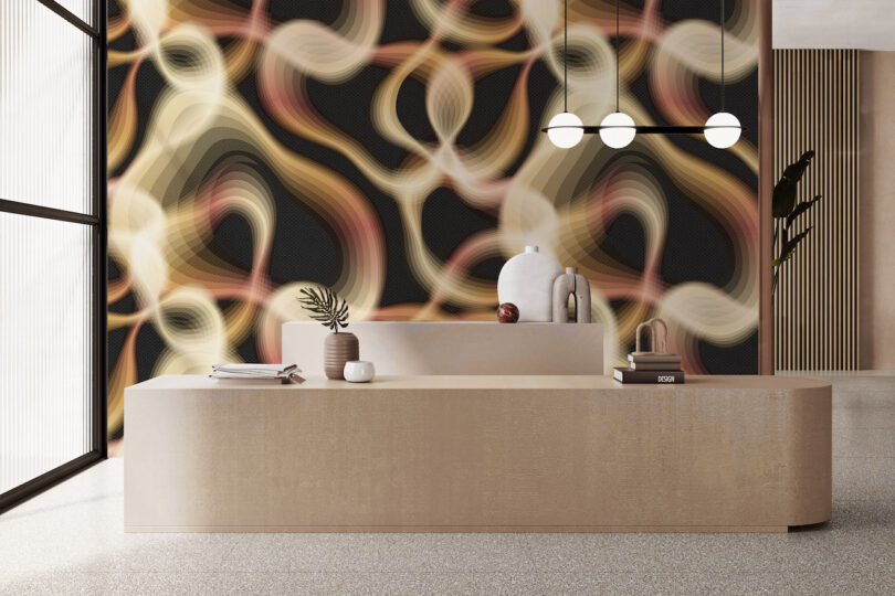 Modern reception area with a minimalist beige desk, decorative vases, books, hanging lights, and a wall featuring an abstract wavy pattern in tan, gold, brown, and black tones