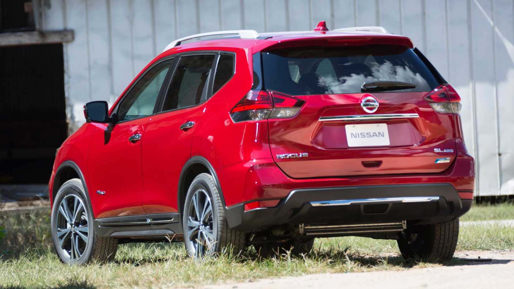 Static rear 3/4 shot of a red 2017 Nissan Rogue Hybrid parked on grass.