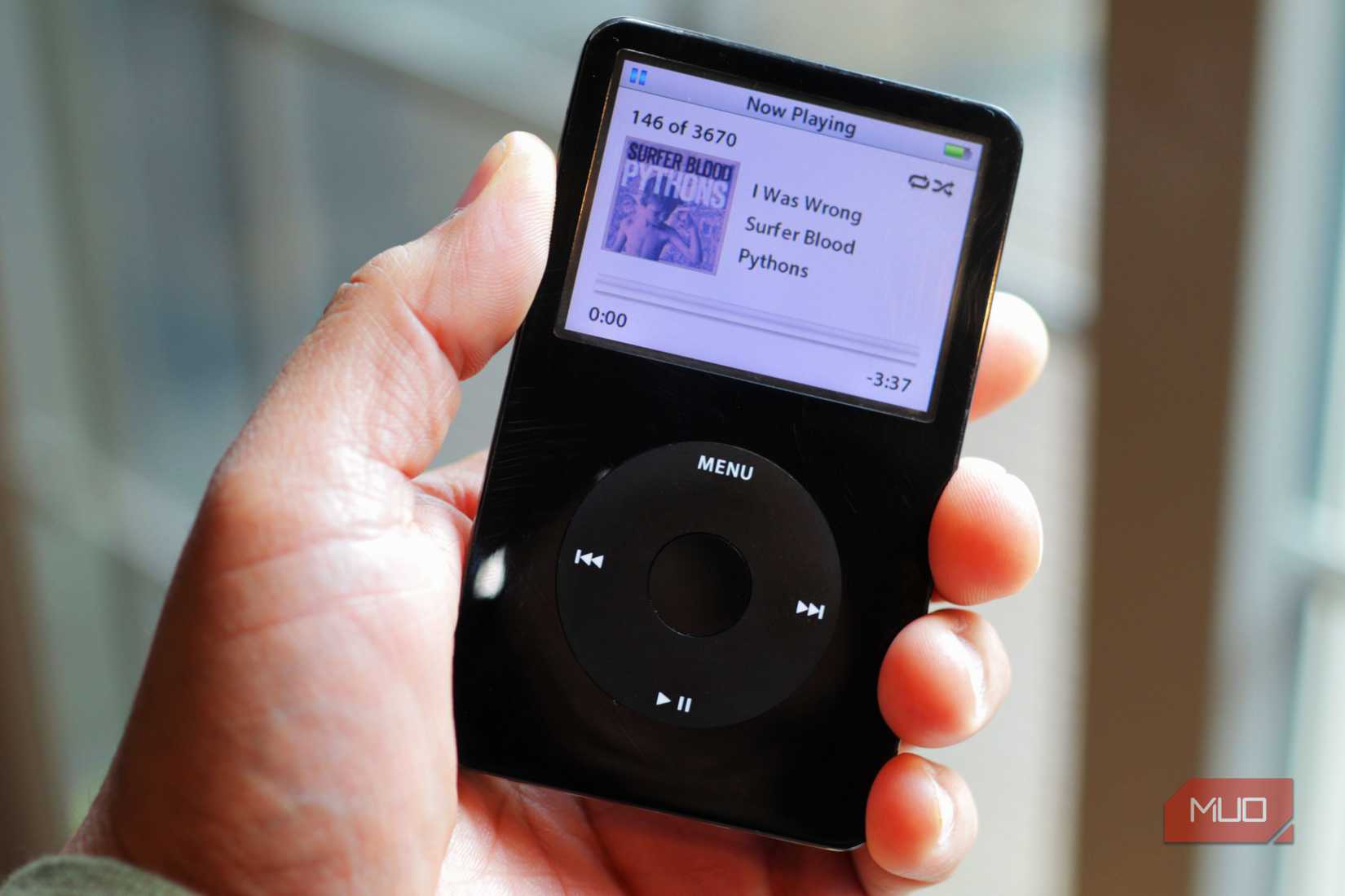 black iPod classic in hand near a window