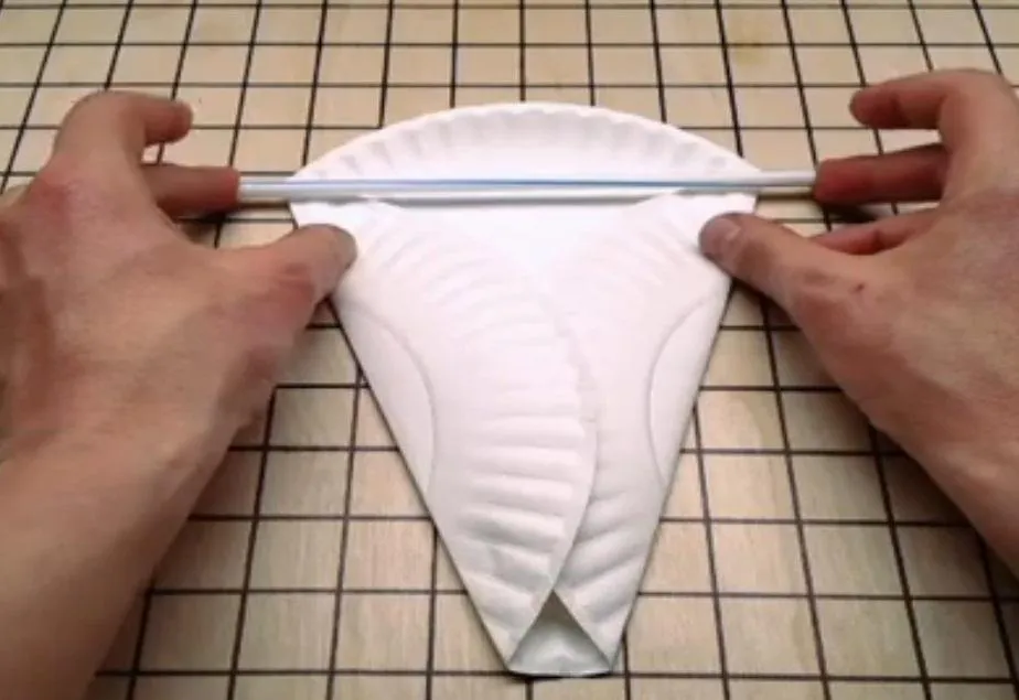Paper plate folded into a triangular shape with a straw placed across it.