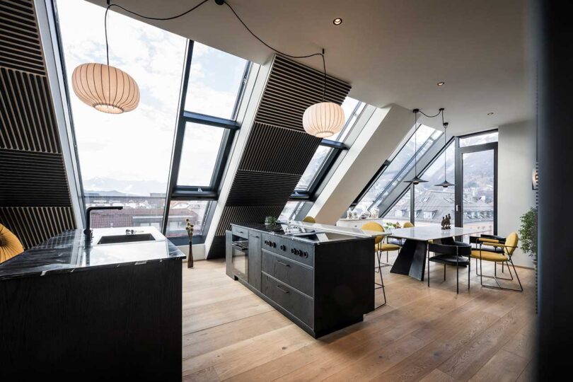 modern apartment interior with slanted glass walls with black kitchen islands in the middle