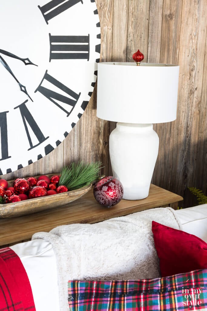 Holiday lamp finial idea. Close up of white table lamp with red Christmas ball ornament made into a finial above the lamp shade.