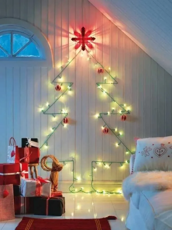 Christmas tree made of lights and decorations in a cozy room with wrapped gifts.